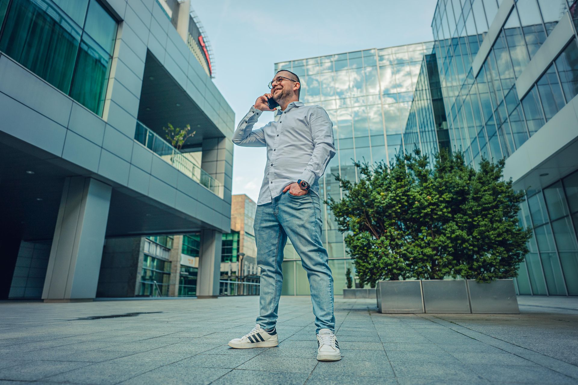 Grzegorz Münnich w miejskim otoczeniu biznesowym rozmawia przez telefon - symbol nowoczesnego podejścia do rekrutacji i budowania zespołów.