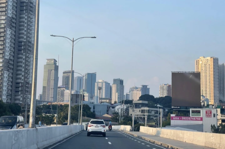 Widok na nowoczesne centrum Manili - Filipiny, z perspektywy ruchliwej drogi miejskiej. Zdjęcie ukazuje charakterystyczną infrastrukturę i skalę urbanizacji, typową dla azjatyckich metropolii.